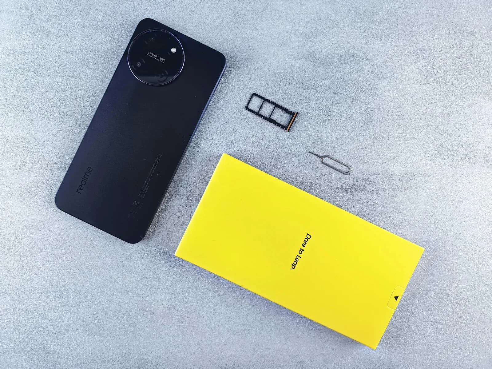 Smartphone with SIM tray, SIM cards, and retail box on a clean surface