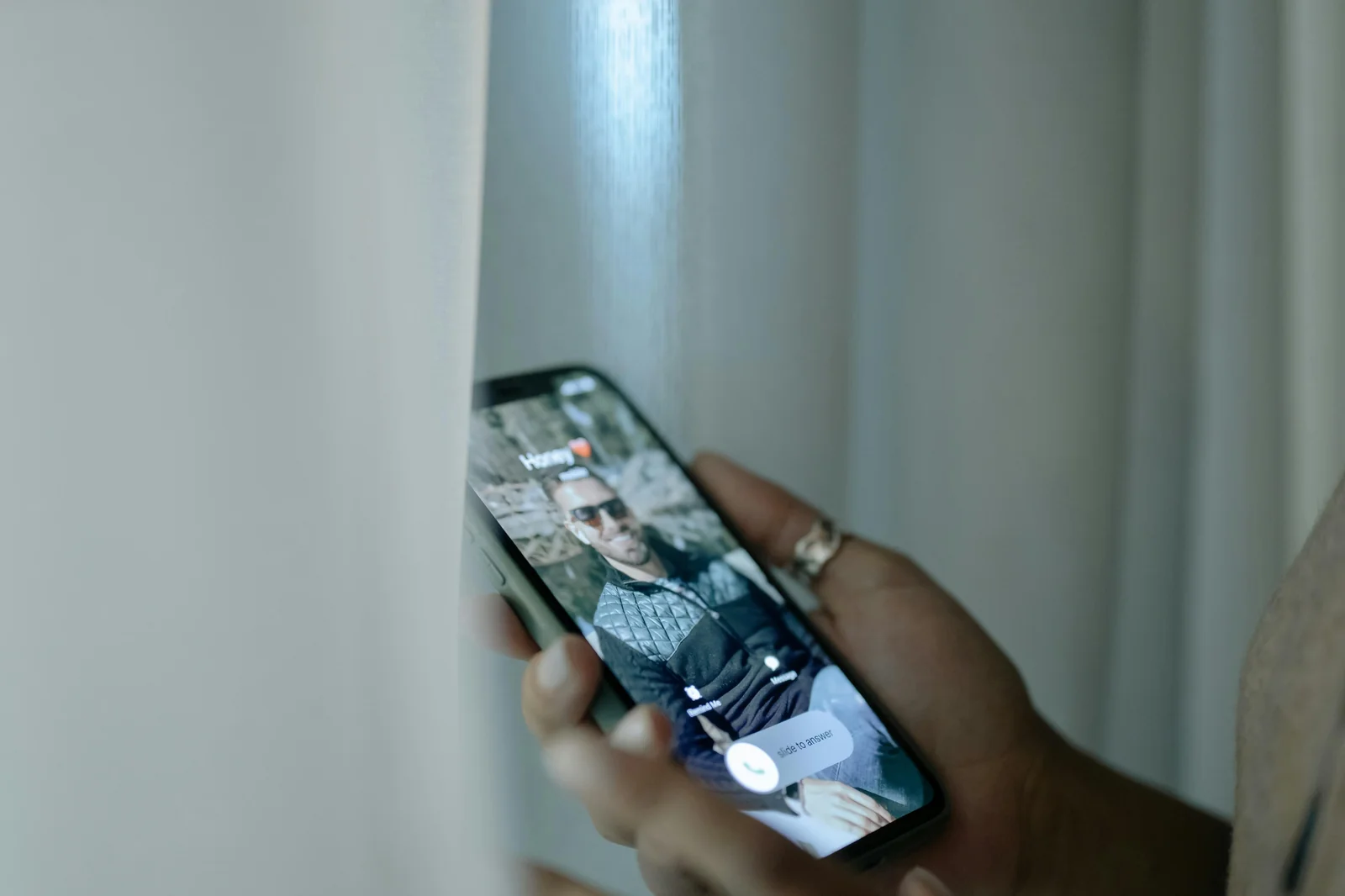 Smartphone showing an incoming call on the screen, held in one hand