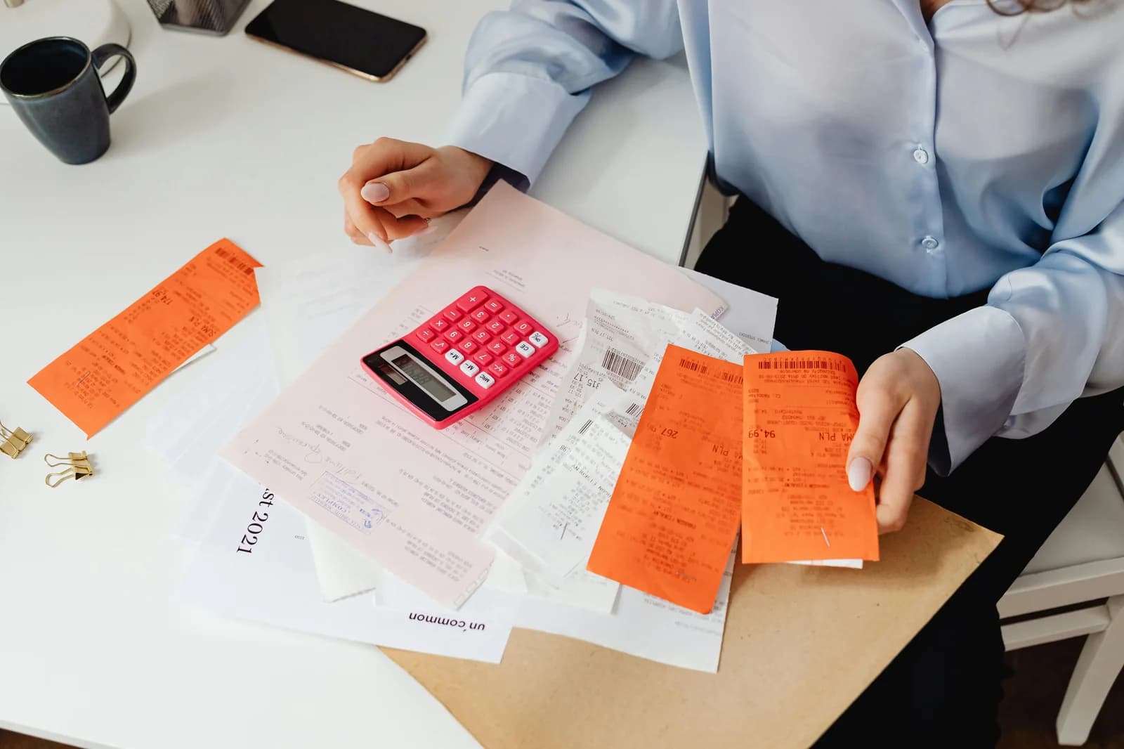 Person reviewing receipts and using a calculator at a desk