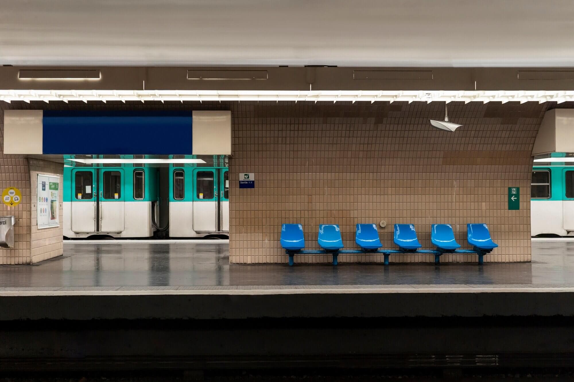 A subway train sits at a platform inside a brightly lit underground station.