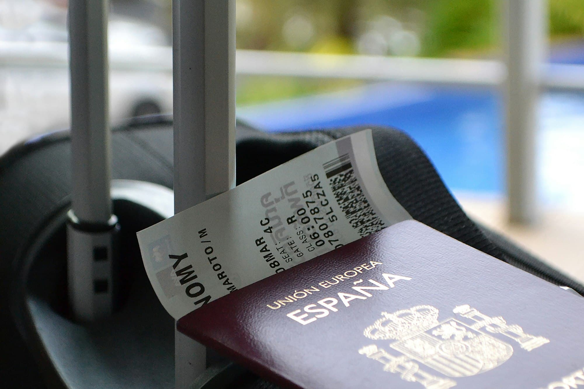 A passport and boarding pass rest beside a suitcase handle, suggesting easy international departure.