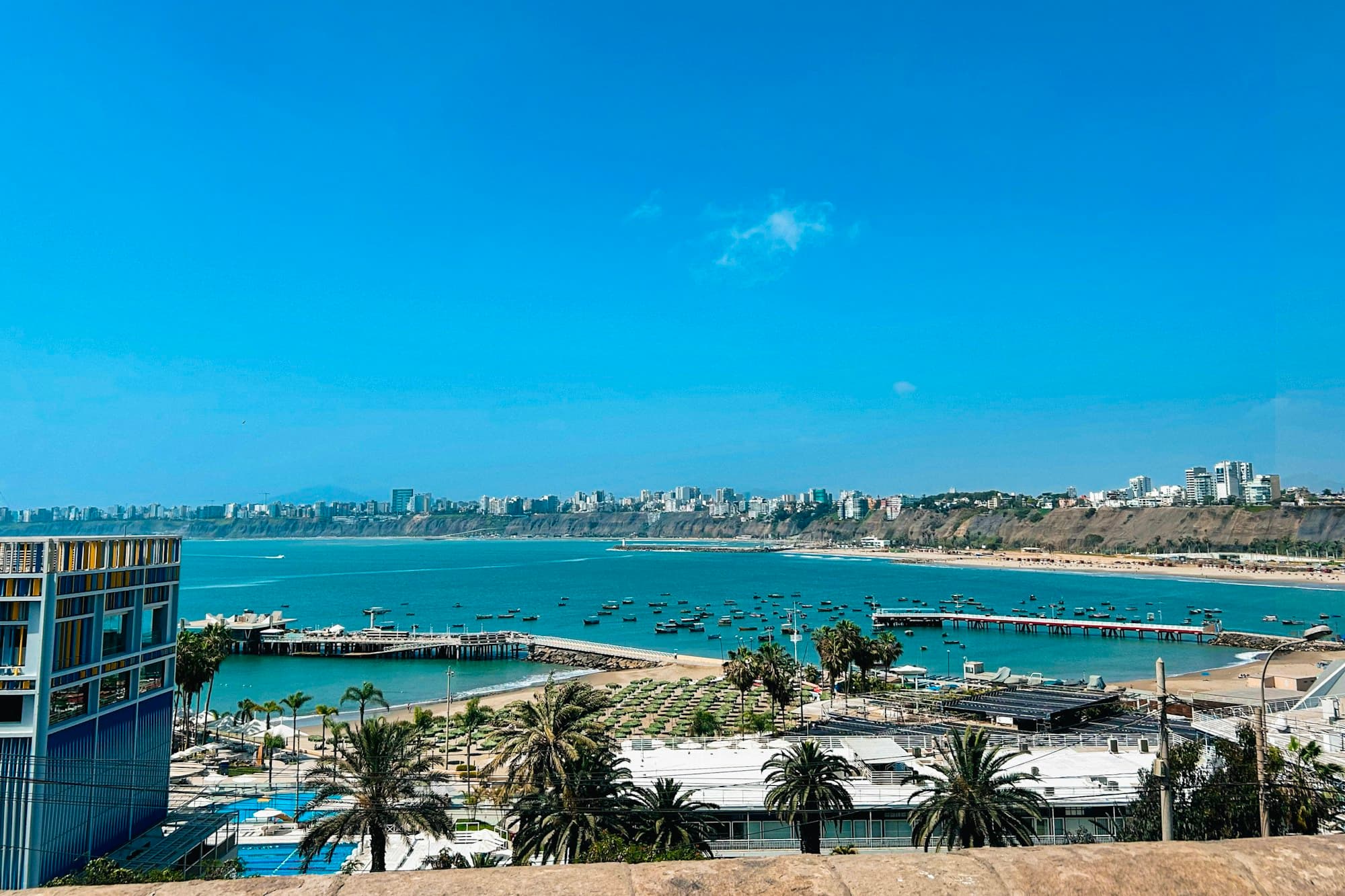 A coastal city skyline rises above a bright waterfront harbor.
