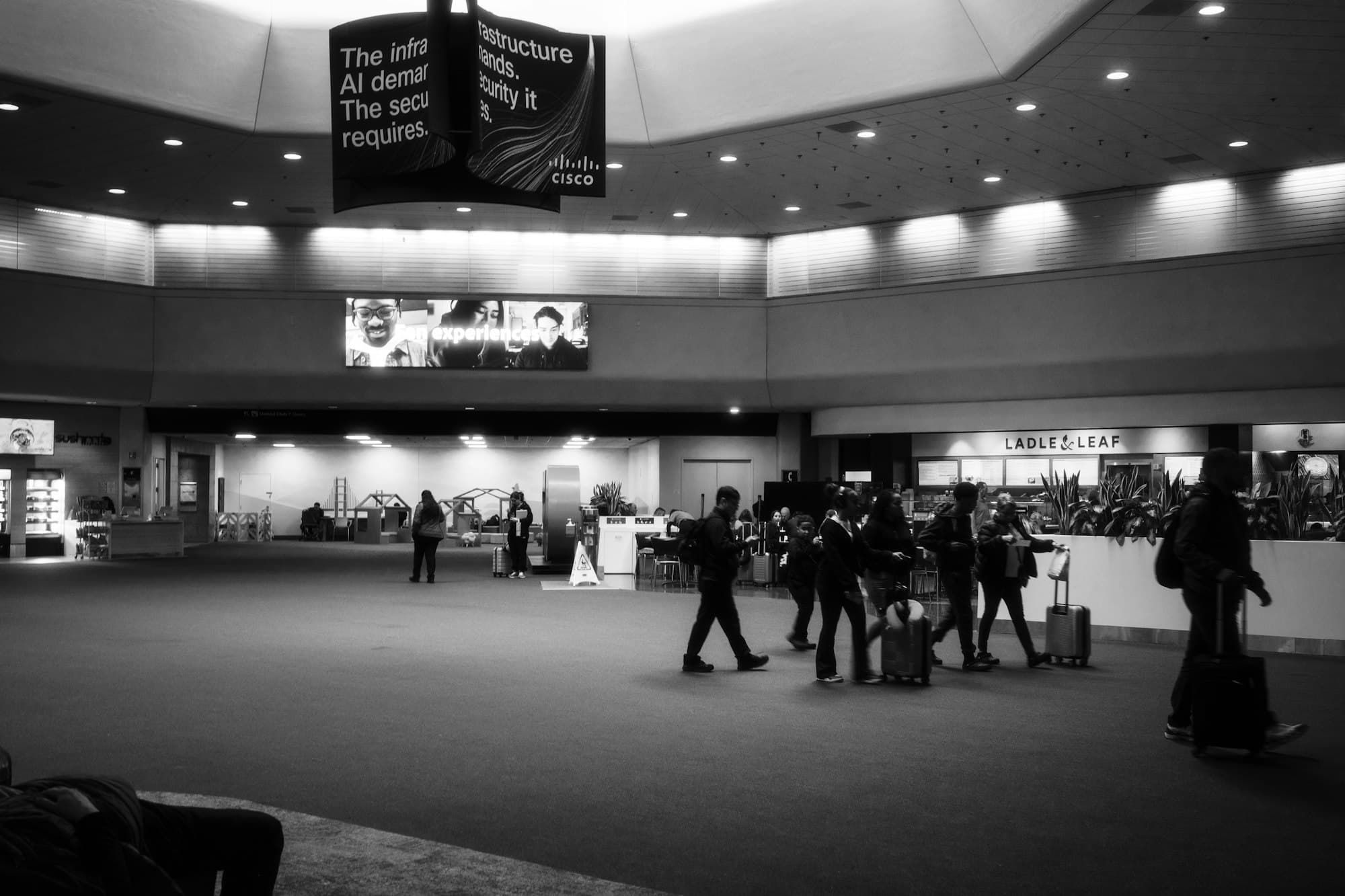 People with suitcases stand in a bright modern airport terminal.