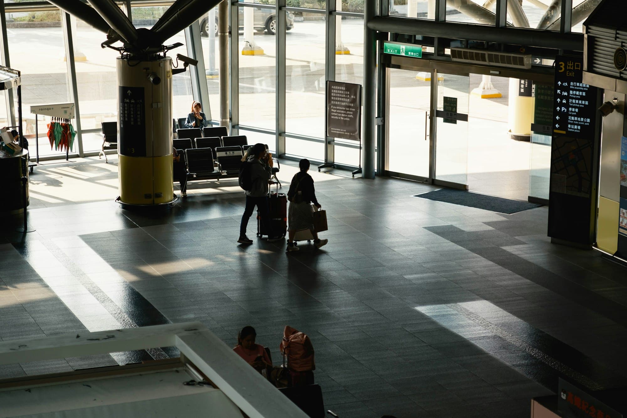 Travelers with luggage move through a bright airport concourse.