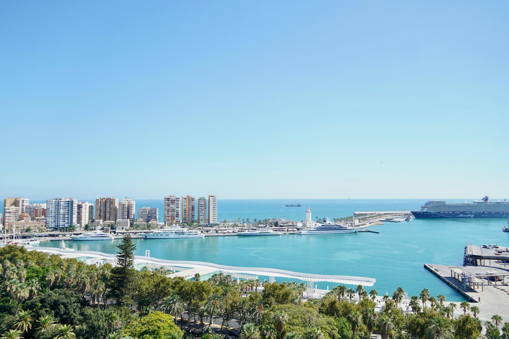 A cruise ship sits beside a dense waterfront skyline.