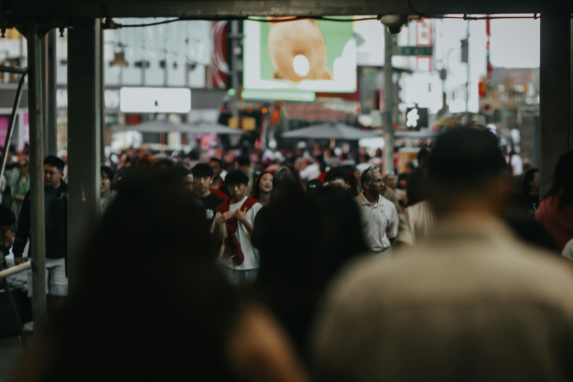 People walk through a crowded city street lined with tall buildings.